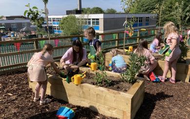 A photograph of children playing in the outdoor classroom, overlooking a school playground