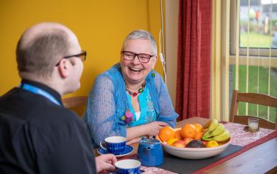 A man and a woman sitting at a kitchen table laughing
