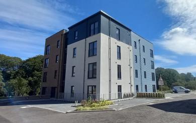 A residential block building with multiple colours and textures on the exterior.