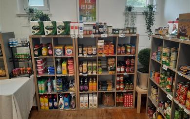 A collection of supermarket items including canned goods, sauces, dried goods and cleaning supplies stacked on wooden shelves