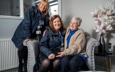 Three women in a living room smiling