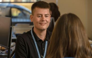 Sanctuary Scotland employee wearing a black polo top and Sanctuary Scotland lanyard talking to a colleague