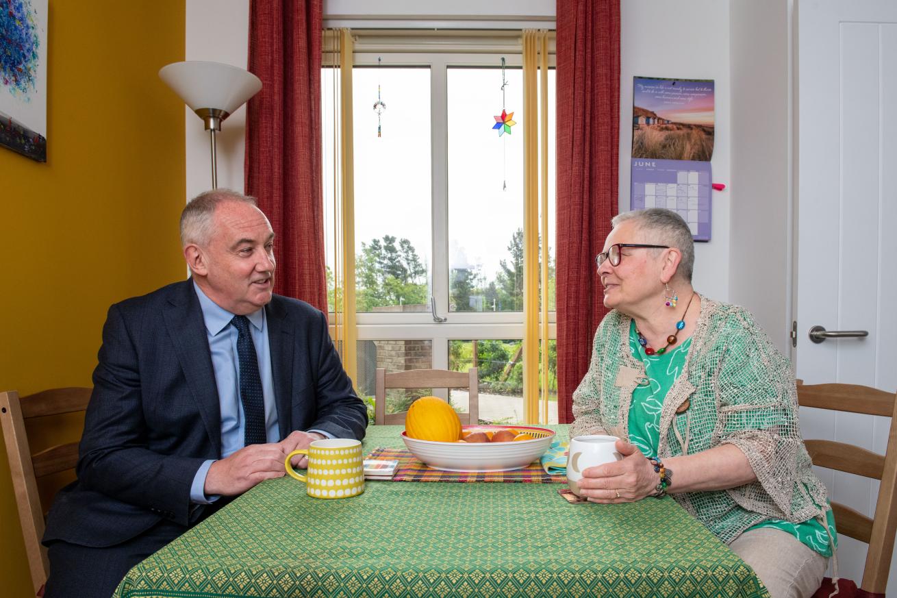 Paul McLennan and Frances Park Two people sitting at a kitchen table and talking with cups of tea