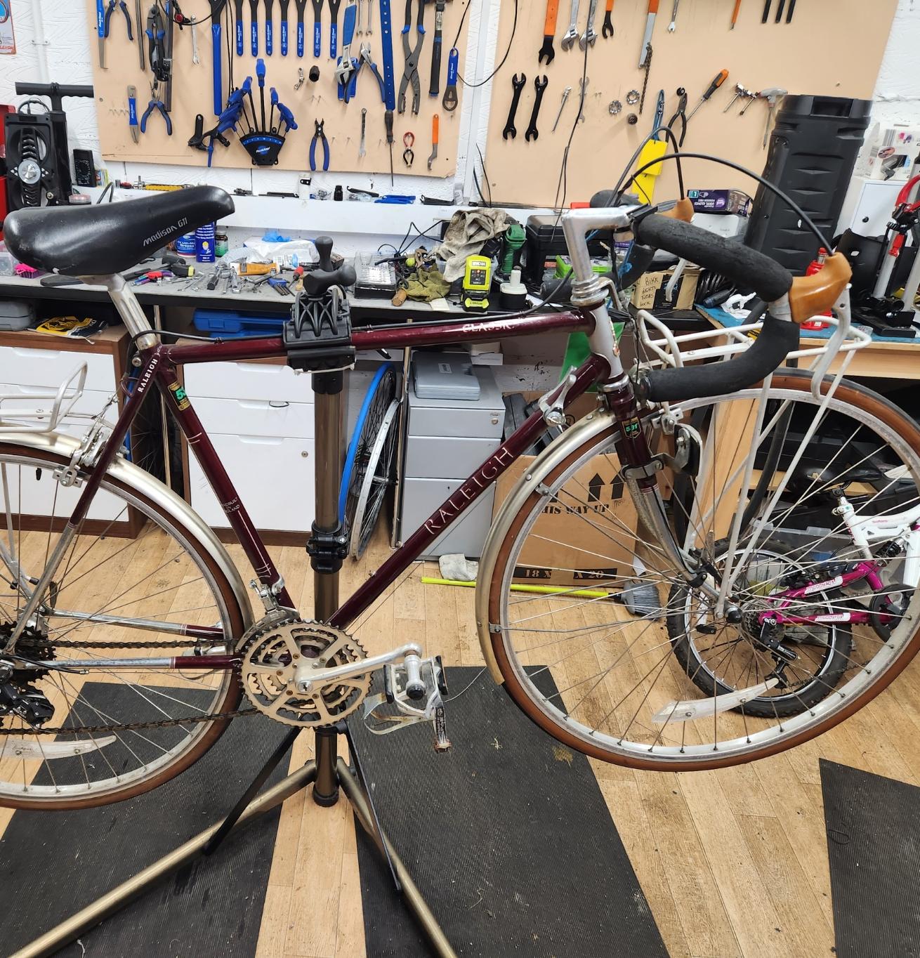 A bike that is suspended on a stand inside a workshop surrounded by tools