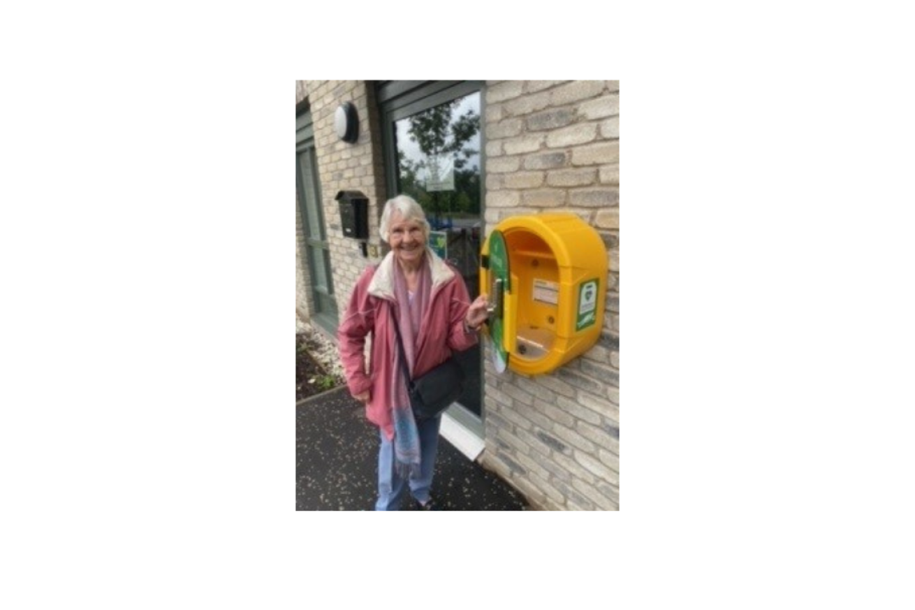 A female member of Kildrum Community Council unveiling the new defibrillator and smiling