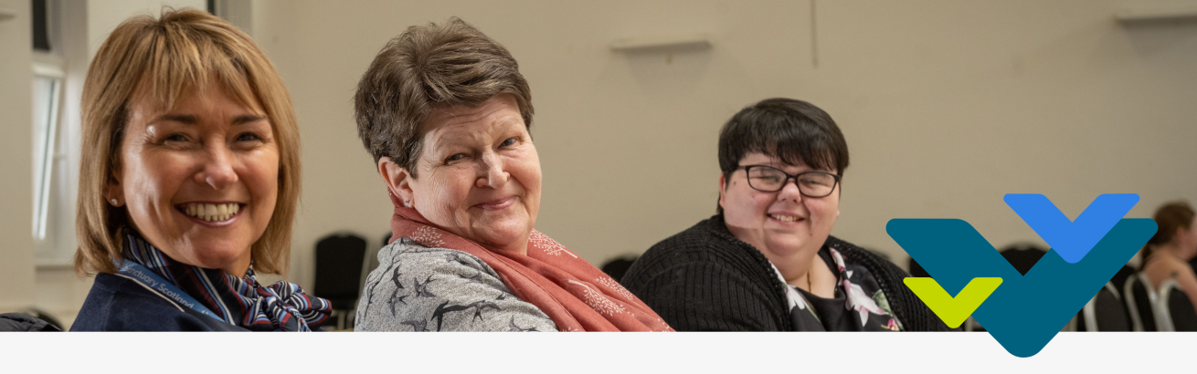 Three smiling people sitting inside a spacious hall