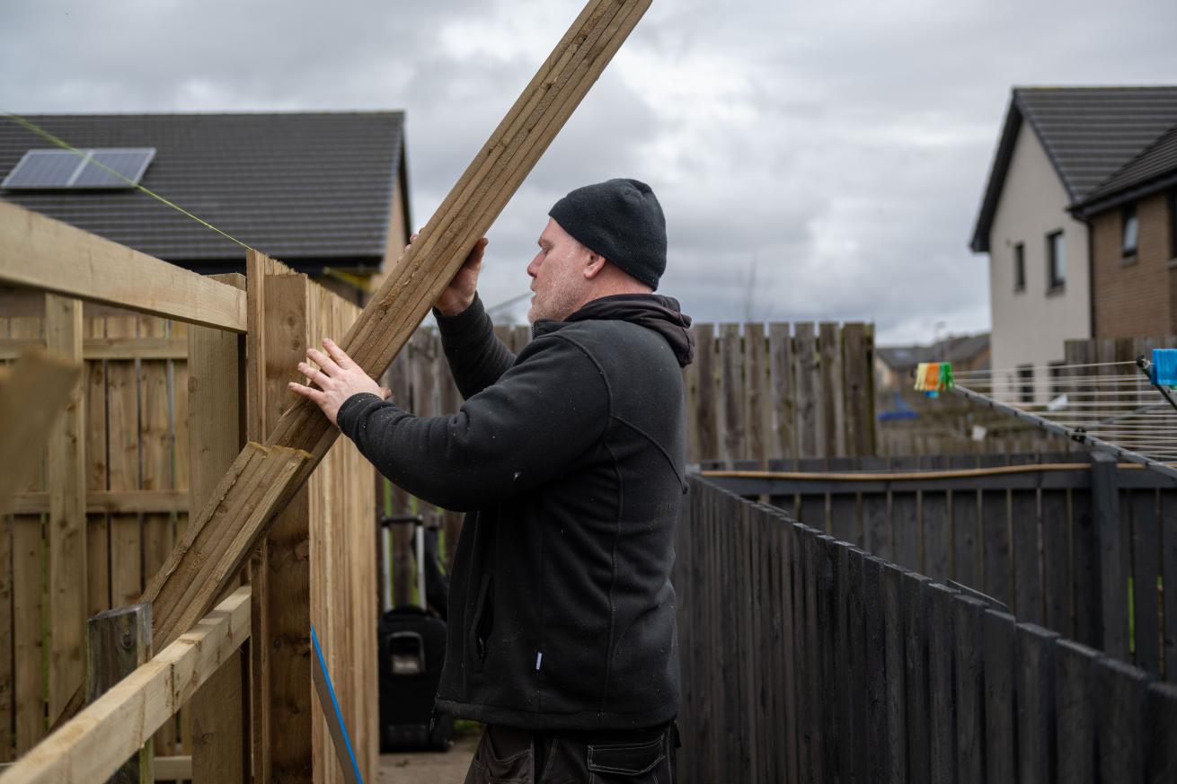 A Sanctuary maintenance worker building a wooden fence