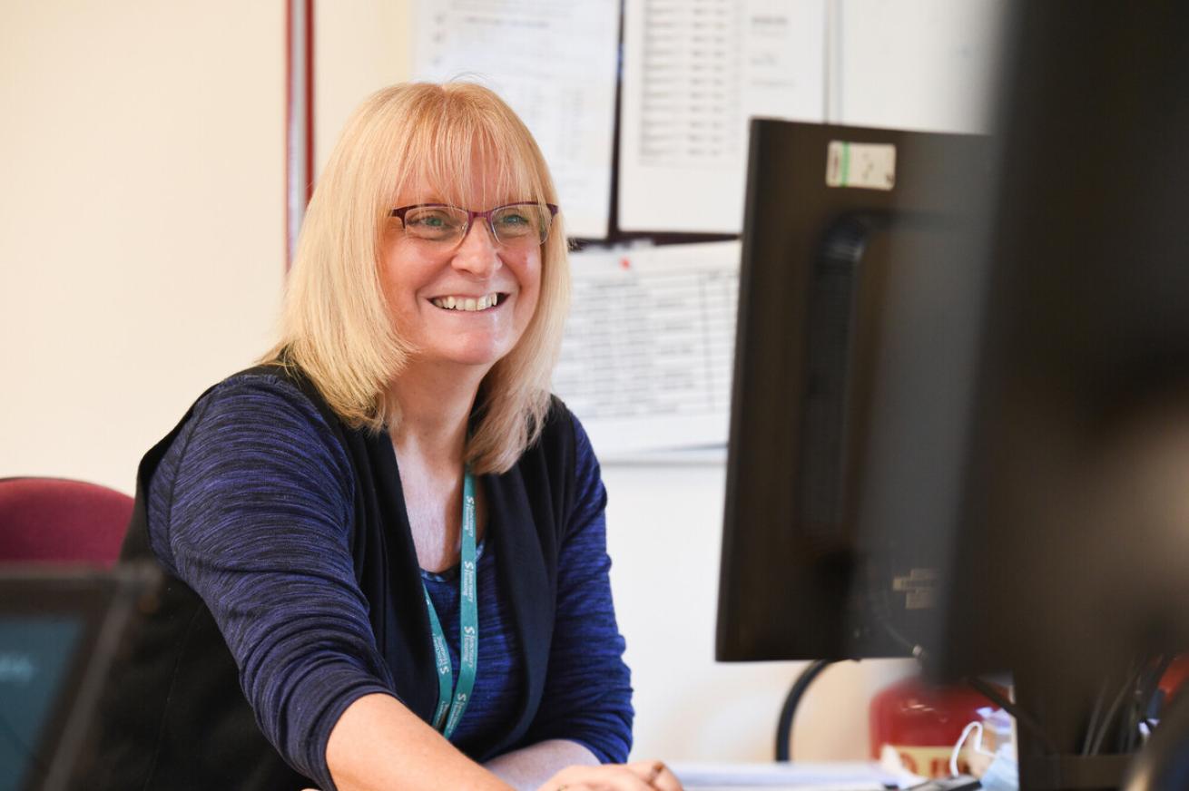 A blonde female Sanctuary income officer working at a desktop computer