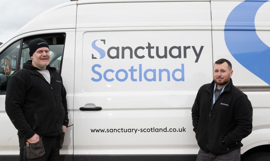 Two men wearing black fleeces with Sanctuary branding stood in front of a white van with Sanctuary Scotland branding on