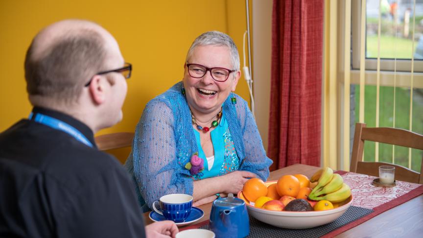 A man and a woman sitting at a kitchen table laughing