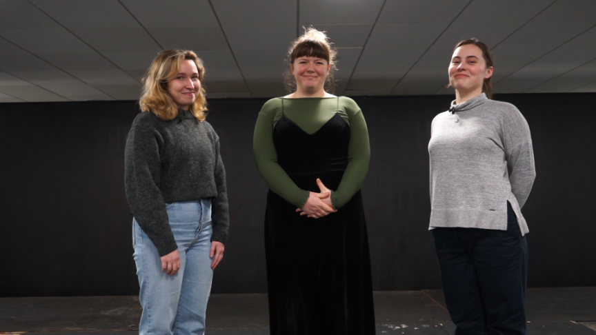 Three women standing in a room smiling