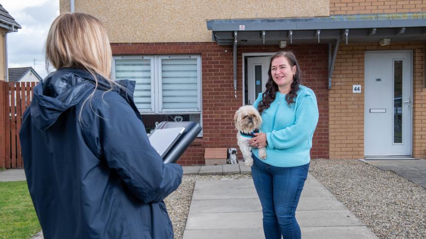 A woman with a dog smiling at a housing officer
