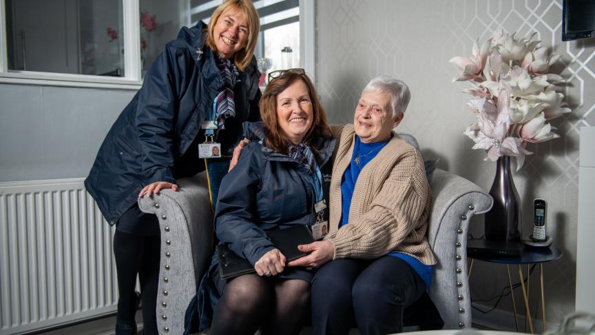 Two Sanctuary staff members with a female resident in her living room