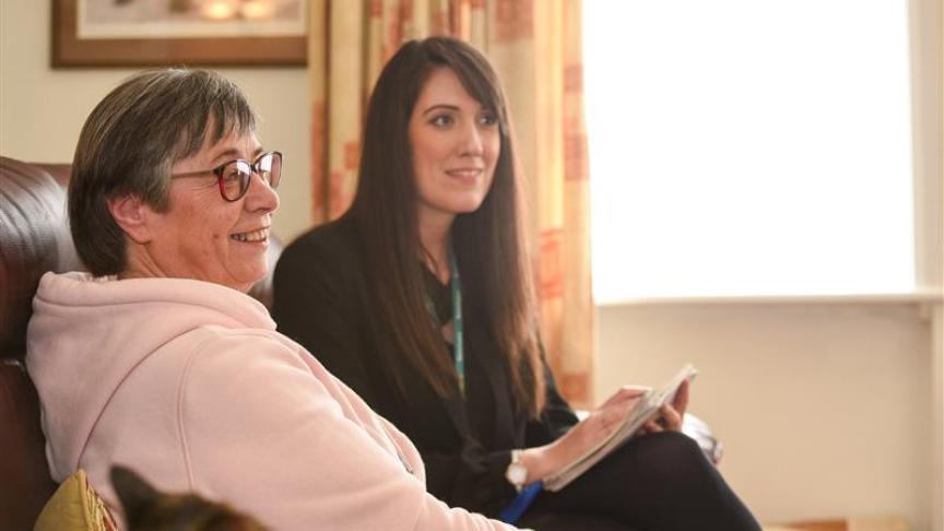 A Housing Officer and a resident sat on a sofa together in the residents home