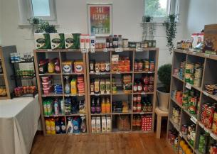 A collection of supermarket items including canned goods, sauces, dried goods and cleaning supplies stacked on wooden shelves