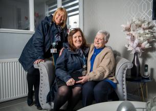 Two Sanctuary staff members with a female resident in her living room