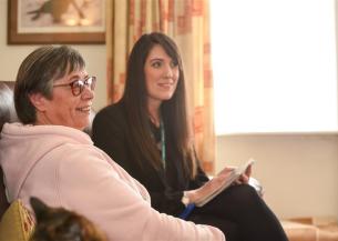 A Housing Officer and a resident sat on a sofa together in the residents home