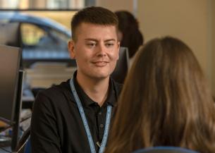 Sanctuary Scotland employee wearing a black polo top and Sanctuary Scotland lanyard talking to a colleague